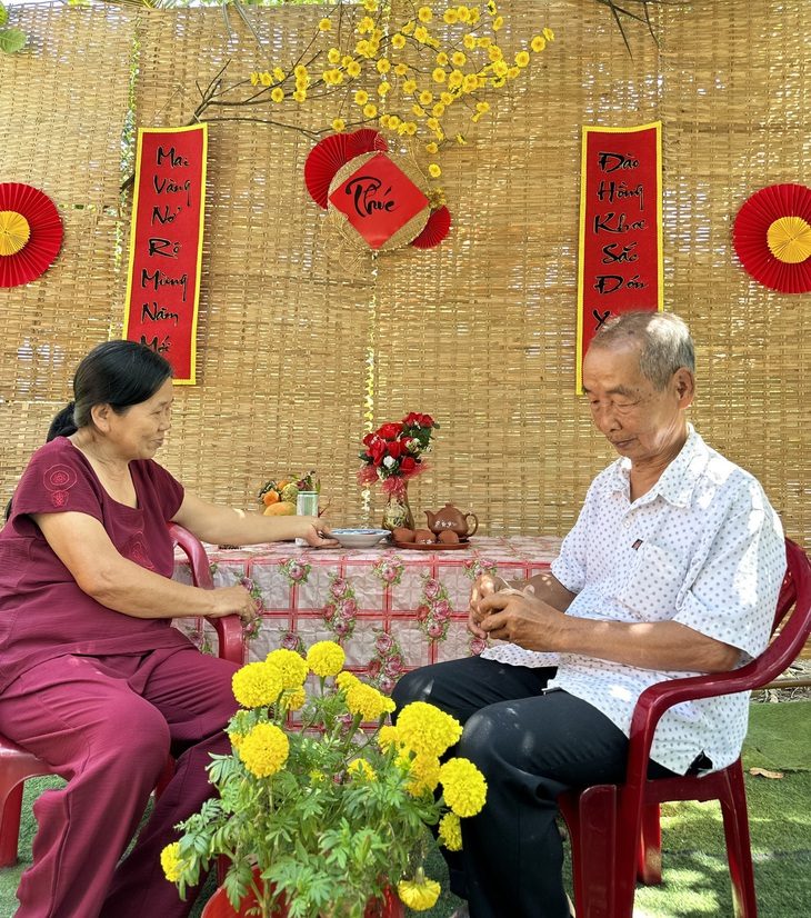 Ông bà chụp hình kỷ niệm bên tiểu cảnh Tết do cháu làm.