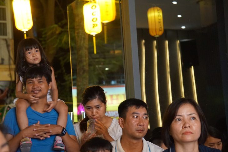 Em bé ngồi trên vai cha chăm chú nghe cô chú hát nhạc Trịnh - Ảnh: T.ĐIỂU